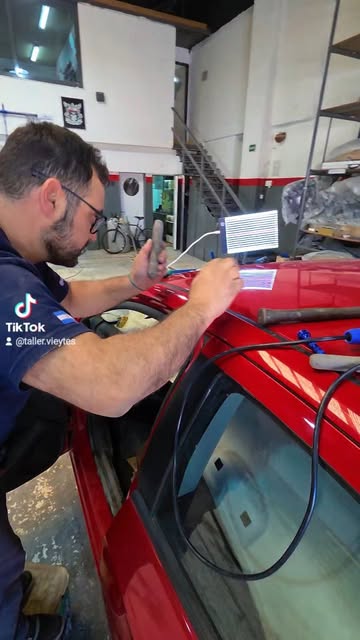 Técnico reparando una abolladura en un auto rojo